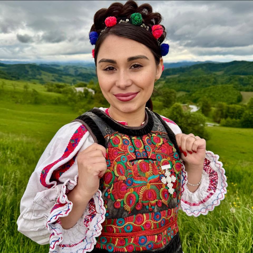Andreea Ghițiu în costum popular, pe dealuri înverzite